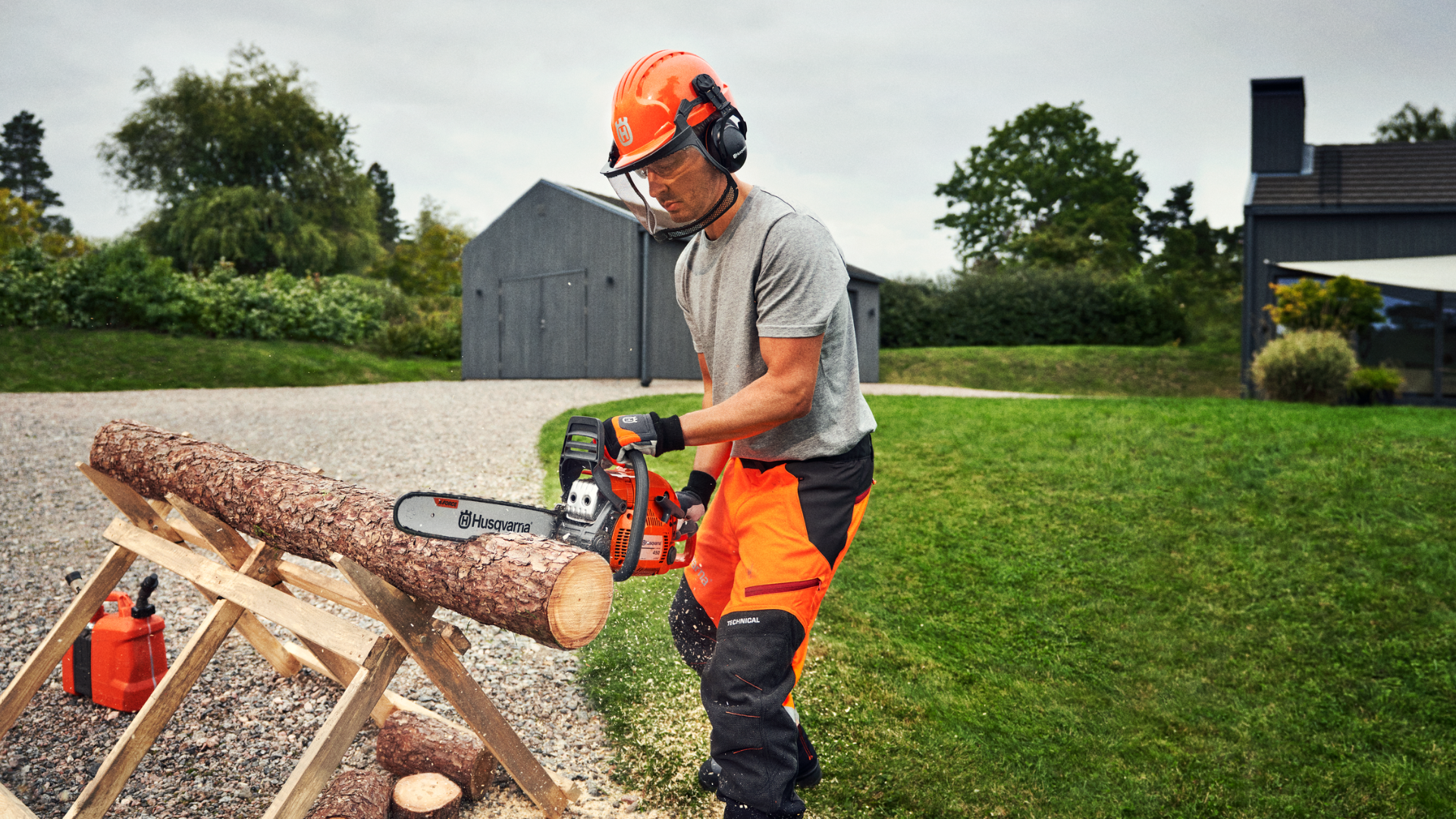 man cutting up log in backyard